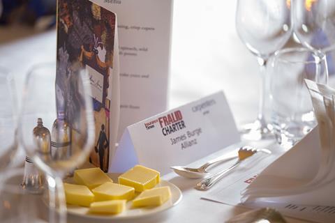 Photograph of a placeholder for the roundtable. Allianz fraud manager James Burge's name is on a card, sat between a plate of cube-shaped striped butter, wine glasses and the menu for event.